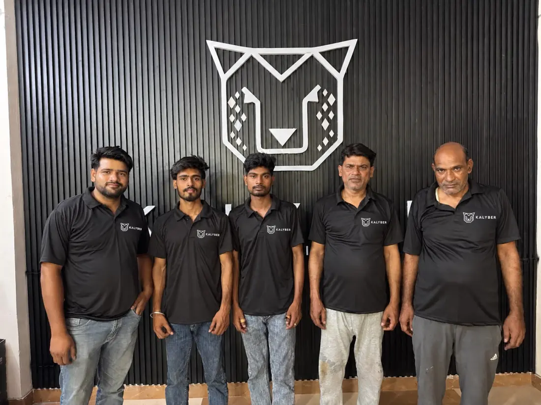 The KALYBER factory team standing in front of the cheetah logo wall